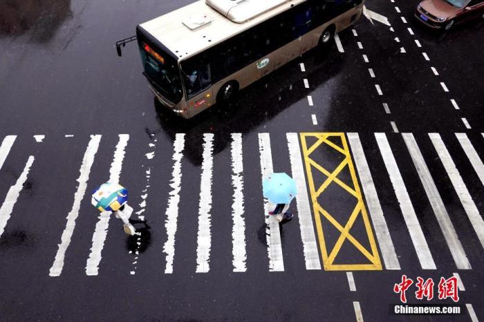 资料图：河南郑州，市民在风雨中出行。 中新社记者 王中举 摄